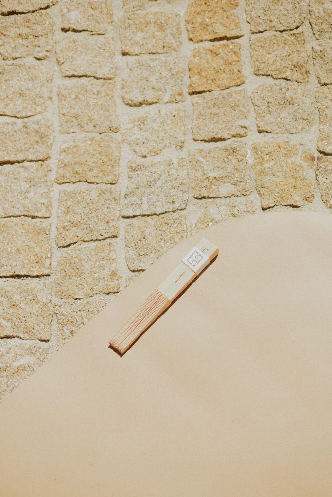 Éventail personnalisé Maison Susa posé sur un élément de décor beige